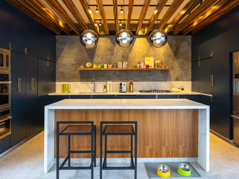 Cocina de Casa Seto con gabinetes azules, isla de madera y plafón de listones